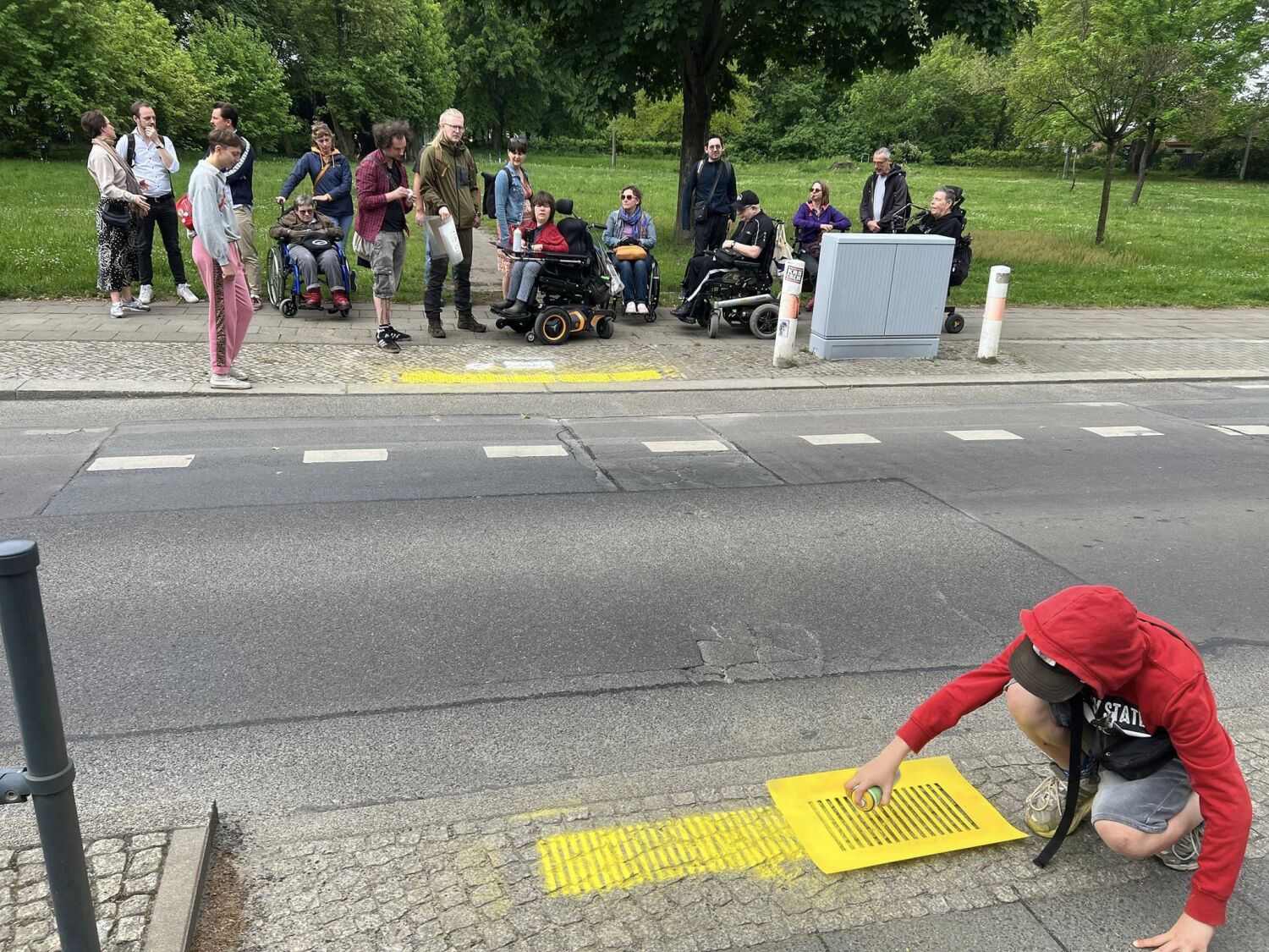 Mithilfe von gelbem Kreidespray wird beim Überweg zur Straßenhaltestelle "Orankestrand" kenntlich gemacht, dass ein Leitsystem für Menschen mit Sehbehinderungen fehlt.