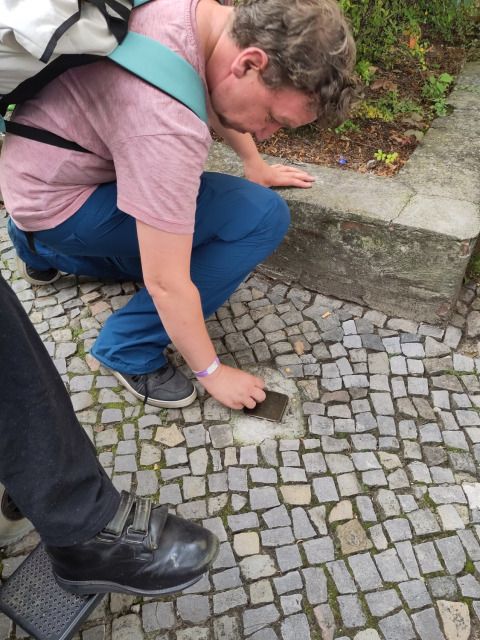 Bildvergrößerung: Ein Beiratsmitglied putzt den Stolperstein von Gottfried Arno Salomon in der Deutschmeisterstraße 1.
