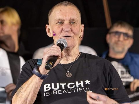 Annet am Mikrofon, trägt schwarzes T-Shirt auf dem in weißer Schrift "Butch* is beautiful" zu lesen ist