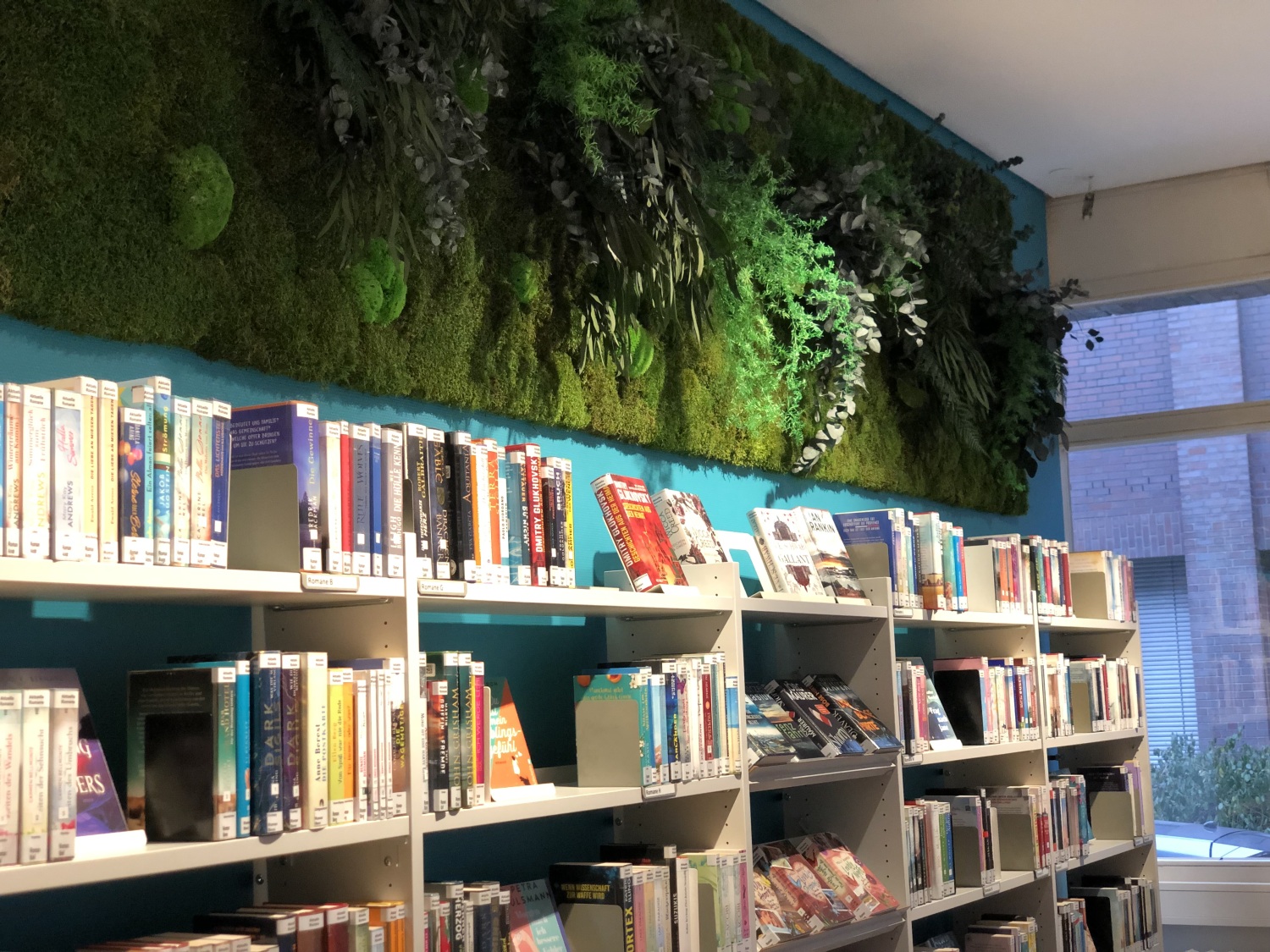 Bücherregal unter einer grünen Mooswand