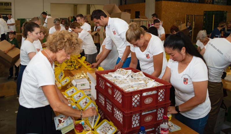 Auch Freiwillige aus dem Bezirksamt Neukölln packen mit Bezirksbürgermeister Martin Hikel die Bio-Brotboxen.