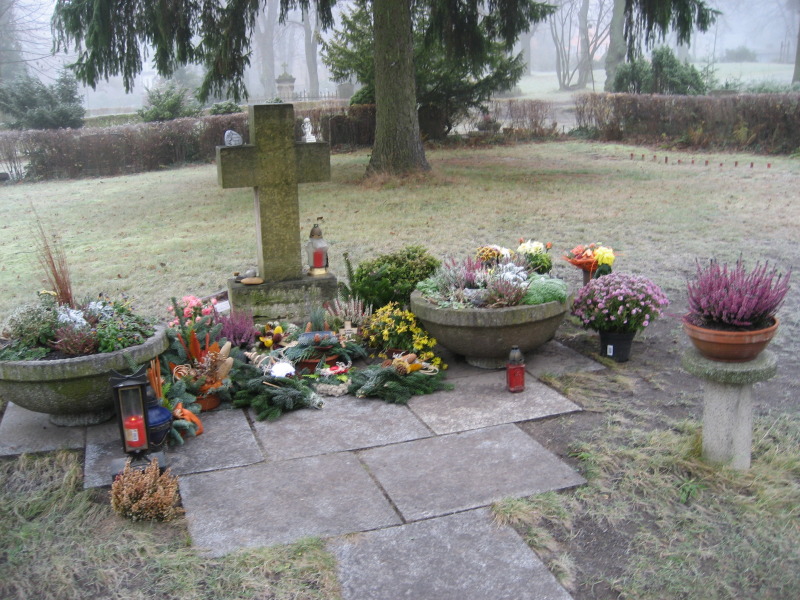 Rasenfläche mit Grabstellen für anonyme Urnenbeisetzung, Blumen vor einem Kreuz