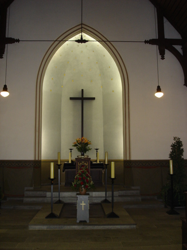 Ansicht des Altarbereichs der Feierhalle Kisseln, Altar mit Kreuz, Kerzen und Pflanzen