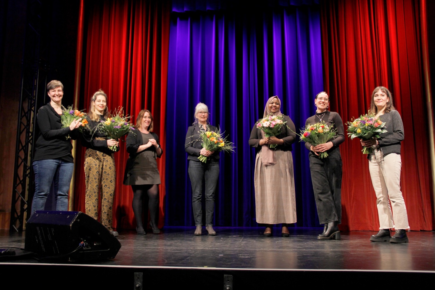 Acht Frauen auf Bühne mit Blumen