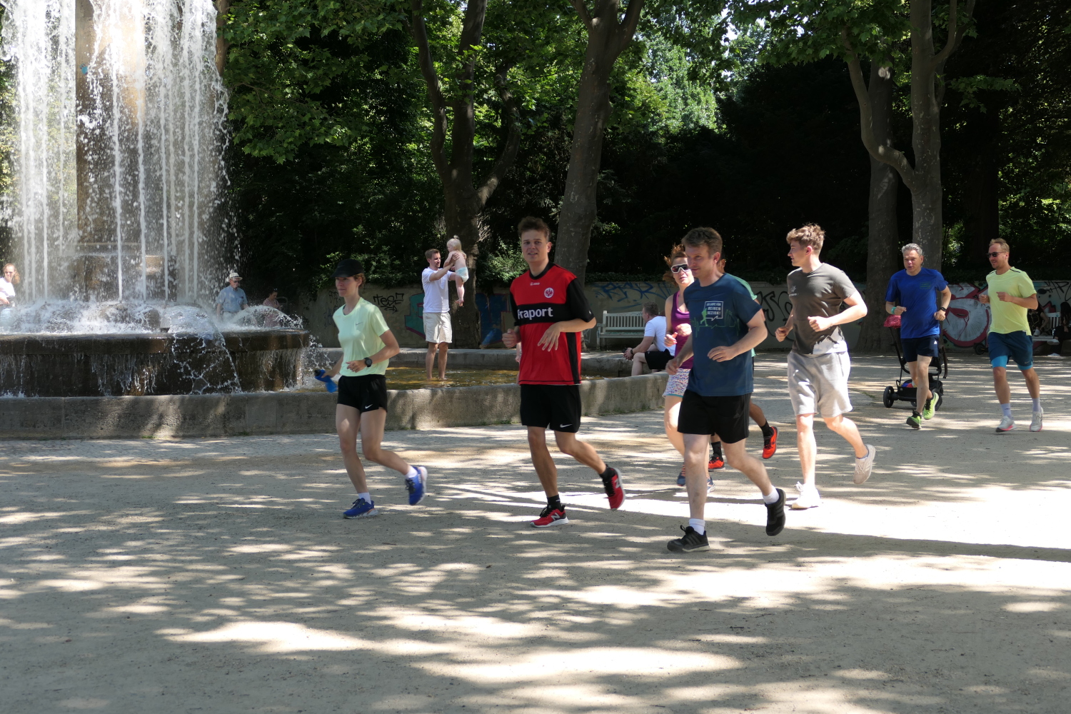 Eine Gruppe läuft vor dem Hintergrund eines Brunnens