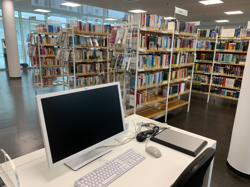 Beratungsplatz mit Computer und Blick auf Bücheregale