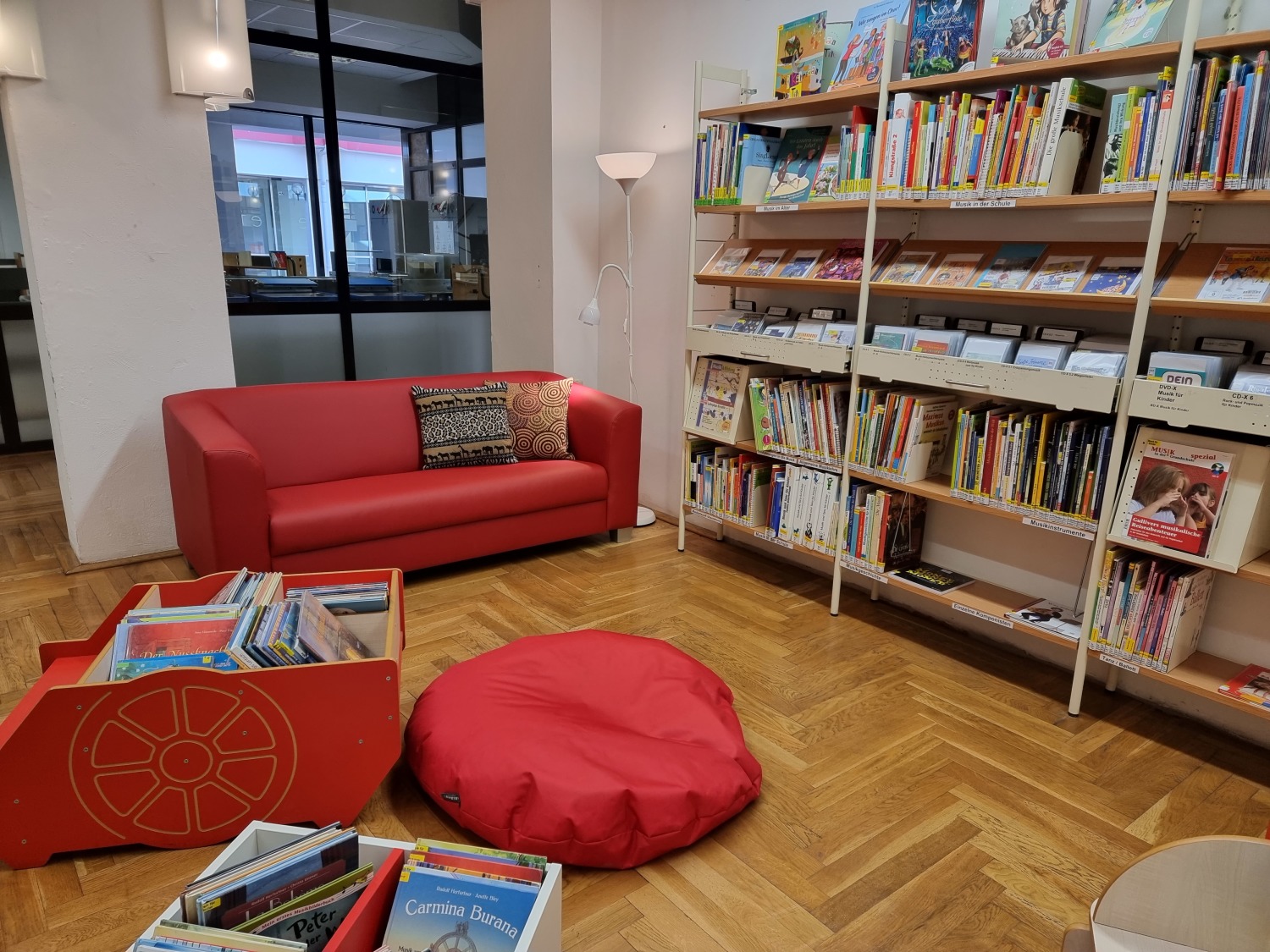 rotes Sofa, roter Büchertrog, rotes Sitzkissen vor Bücherregalen
