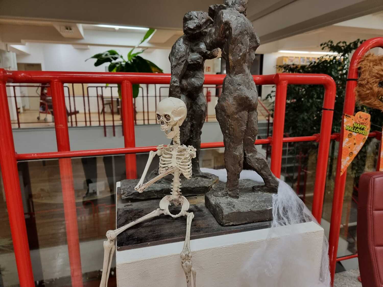 Skelett sitzt vor Skulptur