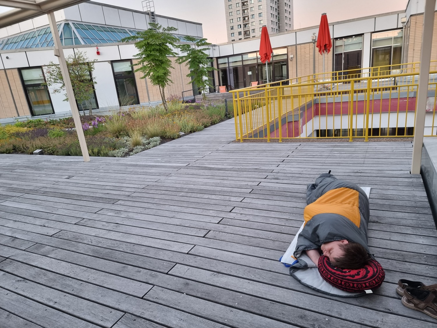 ein Jugendlicher liegt im Schlafsack auf der Dachterrasse