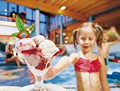 Kleines Mädchen mit großem Eisbecher in einem Erlebnisbad