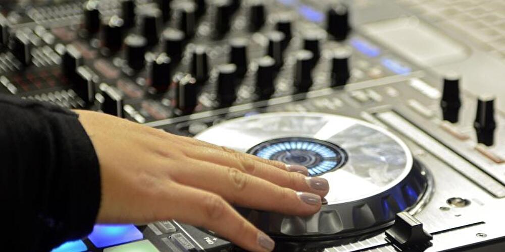 Hand einer jungen Frau am DJ-Pult