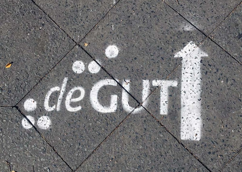 "deGUT"-Logo in weiß auf die Straße gesprüht als Wegweiser