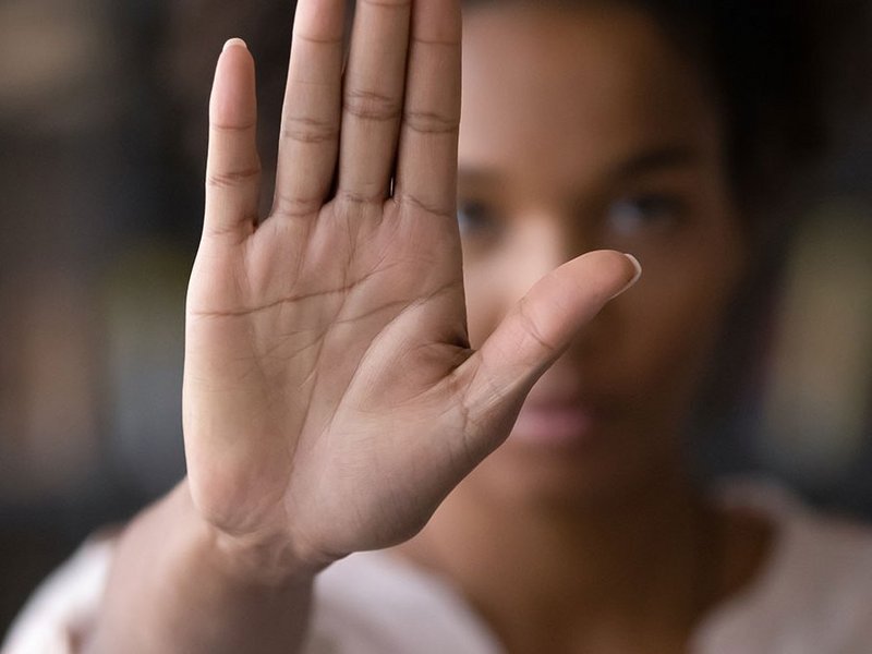 Eine schwarze Frau hat ihre Hand ausgestreckt und zeigt die Handfläche als Zeichen gegen Rassismus und Diskriminierung.
