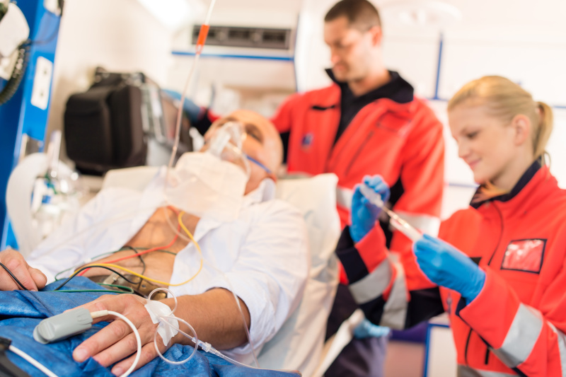 Liegender Patient wird von zwei Sanitätern in Rettungswagen medizinisch versorgt