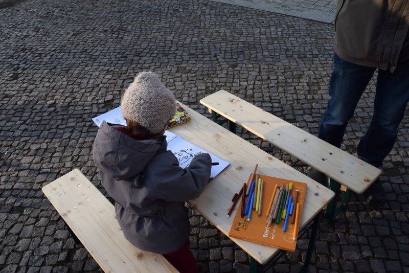 Ein Kind sitzt am Tisch und malt das Malbuch aus