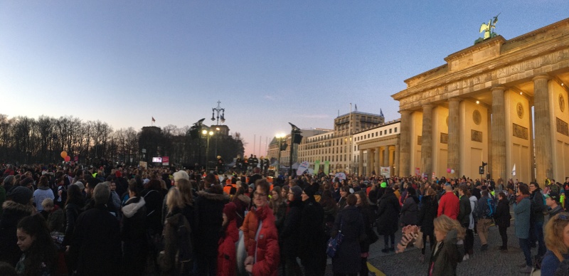 Teilnehmende der Tanzdemo und das beleuchtete Brandenburger Tor