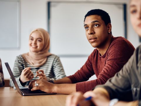 Multiethnische Gruppe Studenten sitzt zuhörend an einem Arbeitstisch