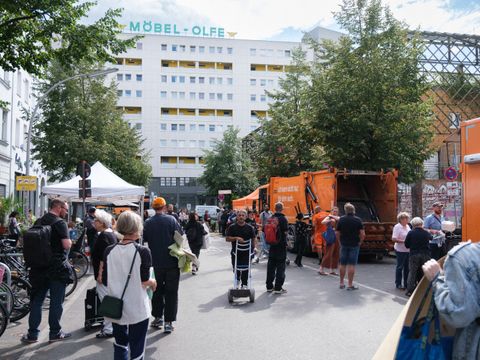 Menschen stehen neben großen Müllfahrzeugen der BSR auf dem Kiezmarkt in der Dresdener Straße