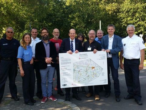 Bezirksstadtrat Tobias Dollase bei der Übergabe der Schulwegpläne an den Stellvertretenden Schulleiter der Kolumbus-Grundschule Herrn Niedergesäß inmitten von Vertreterinnen und Vertretern der Kooperationspartner: Senatsverwaltung für Jugend, Familie und Bildung, Bund für Umwelt und Naturschutz (BUND), Berliner Sparkasse, Gesellschaft für Arbeitsförderung in Köpenick mbH (CÖGA) und Vertreterinnen und Vertreter der für Reinickendorf zuständigen Polizeiabschnitte. (Bild: BA Reinickendorf)