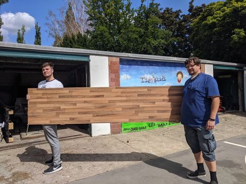 Mitarbeiter Alexander Boese (links) und Martin Jaschuke tragen die große Platte für den Tresen erstmal in die Tietzia-Garage. (Bild: BA Reinickendorf)