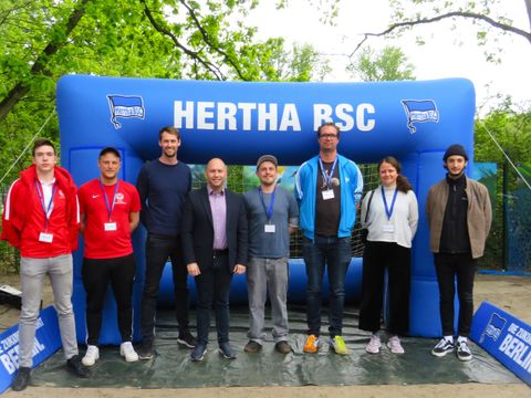 Gruppenfoto aller Partner des Projekts „Zocken gegen Rassismus“, unterlegter Text: ( v.l.n.r.) zwei Vertreter der Antidiskriminierungsstelle des BFV, Nicolas Frevel (Leiter der Strategie Hertha BSC), Alexander Ewers (Jugendstadtrat), Anatolij Krebs (Beteiligungskoordinator), Benjamin Kubel (Leiter des meredo), Antonia Richter (Beteiligungskoordinatorin), Vertreter der Amadeu-Antonio-Stiftung (Bild: BA Reinickendorf)