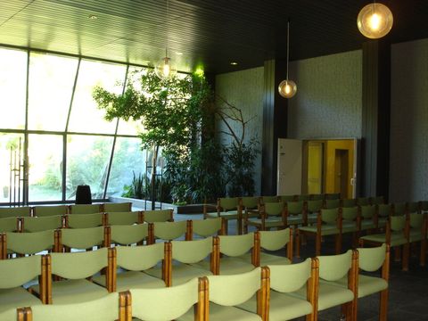Innenansicht der Feierhalle Landschaftsfriedhof Gatowm helle Stuhlreihen, weite Fensterfront