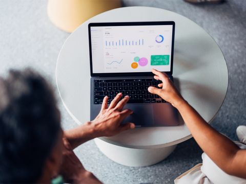 Mann arbeitet an Laptop, auf welchem Statistiken abgebildet sind - Vogelperspektive