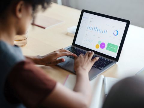 Frau arbeitet an Laptop, auf welchem Statistiken abgebildet sind