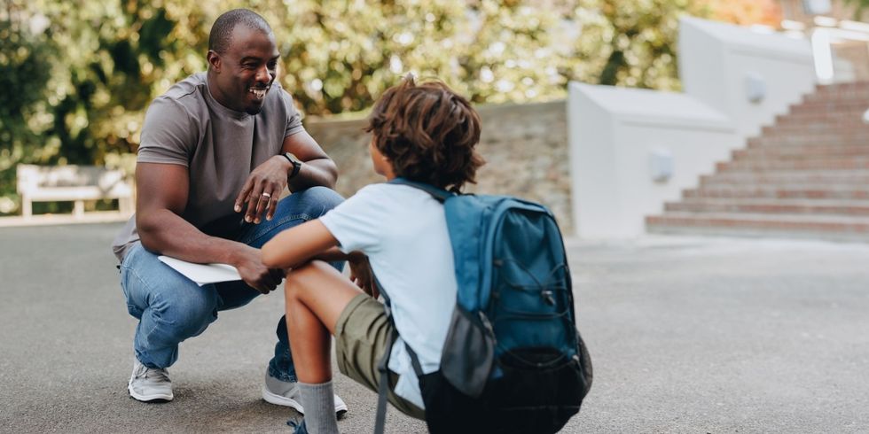 Lehrer unterhält sich mit jungen Schüler auf dem Schulgelände