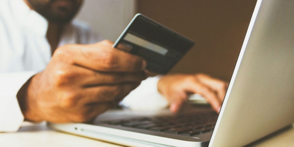 Mann am Laptop hält Bezahlkarte in der Hand und tippt etwas ab