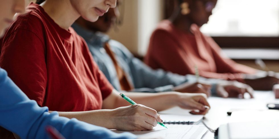 Prüfungssituation in der Universität - Nahaufnahme von dem Tisch und den schreibenden Händen