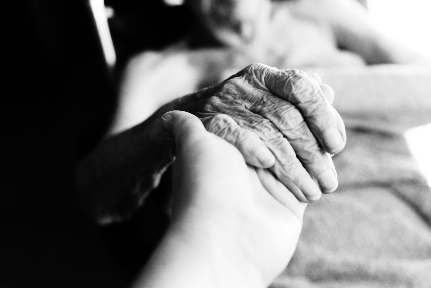 Jüngere Hand hält eine Ältere (s/w)