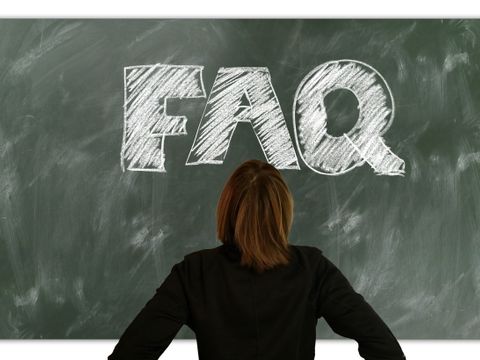 Eine Frau steht vor einer Tafel auf der "FAQ" mit Kreide notiert ist.