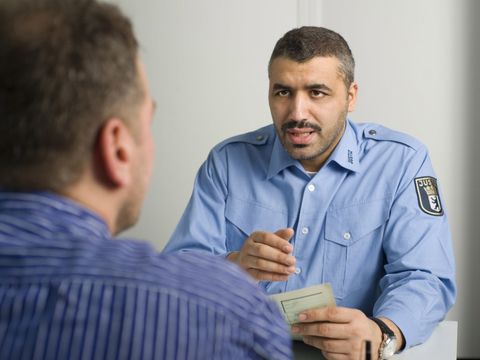 Ein Gefangener wird von einem Justizvollzugsbeamten im Gespraech informiert