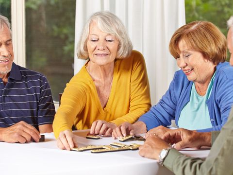 Zwei Seniorinnen und zwei Senioren spielen gemeinsam ein Brettspiel