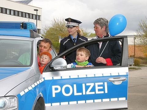 Polizist mit Kindern und Erwachsenen am Polizeiauto