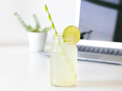 Eine kalte Limonade steht auf dem Arbeitstisch, im Hintergrund ein Laptop.