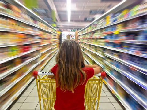 Junges Mädchen schiebt einen Einkaufswagen durch einen Supermarkt