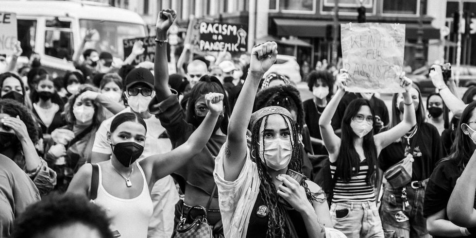 Schwarz-weiß Foto von einer protestierenden Gruppe Menschen mit Schildern gegen Rassismus.