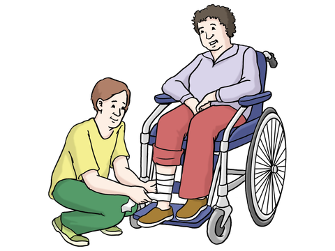 Eine Person sitzt im Rollstuhl und eine andere Person wickelt ihr einen Verband um die Wade