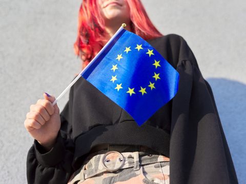 weibliche Person hält EU-Flagge in der rechten Hand