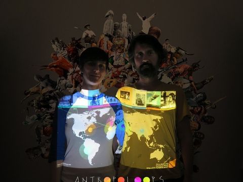 Bildvergrößerung: Ein Mann und eine Frauen stehen nebeneinander und blicken in die Kamera. Beide tragen Pullover, die leuchten und eine Art Bildschirm enthalten.