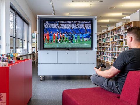 Bildvergrößerung: Mann zockt Fifa am Großbildschirm
