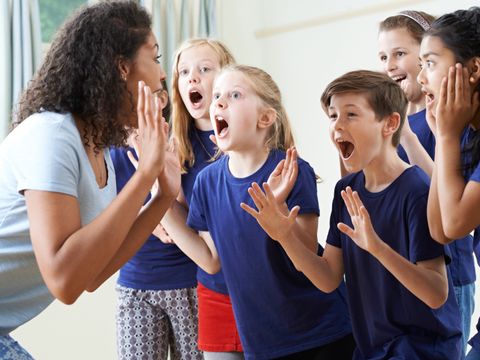 Kindergruppe mit Lehrer genießt gemeinsamen Schauspielunterricht