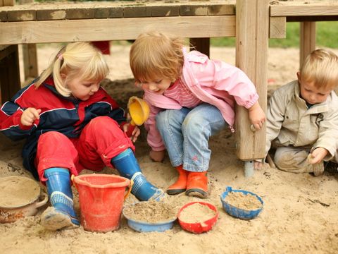 Drei Kinder spielen im Sandkasten einer Kita