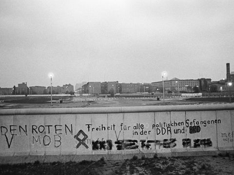 Grenzstreifen mit Fahrzeugsperren und Lichttrasse am Potsdamer Platz. Politische Graffiti sind auf der Grenzmauer 75 geschrieben.