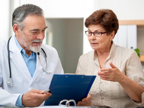 Eine Patientin diskutiert mit ihrem Arzt das Schreiben, welches der Arzt in der Hand hält