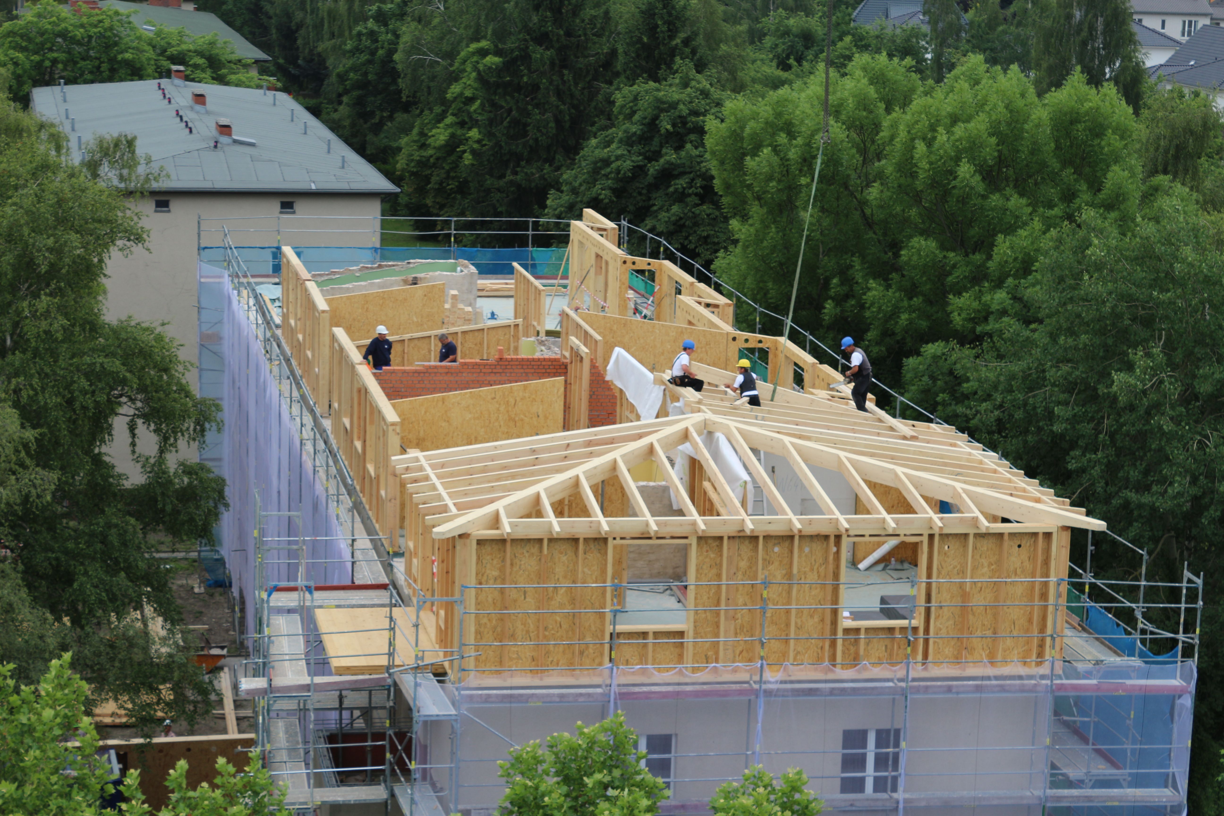 Bauarbeiter errichten mit Holz eine weitere Etage auf einem Wohnhaus