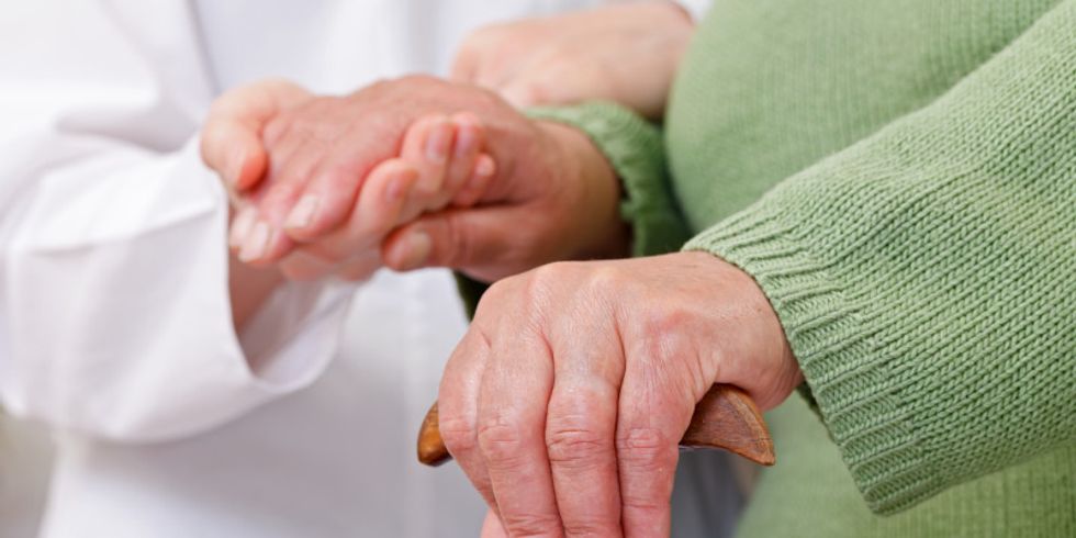 Bildausschnitt Arzt hält Hand von Seniorin mit Krückstock