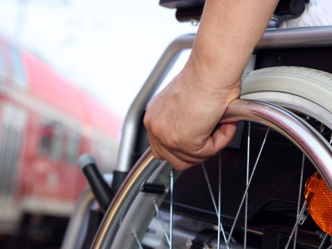 Bildausschnitt: Person in Rollstuhl vor einem Zug